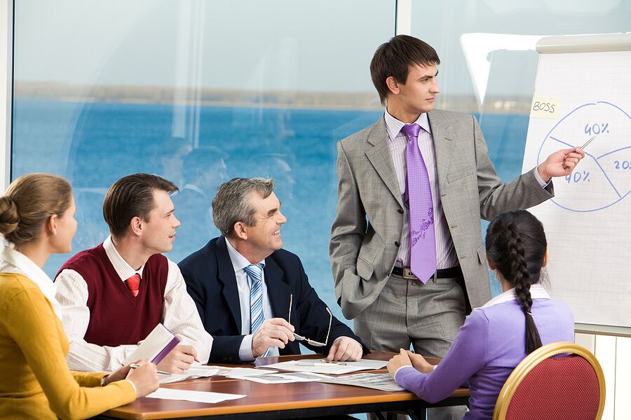 Image of business group listening attentively to their young colleague making presentation on board